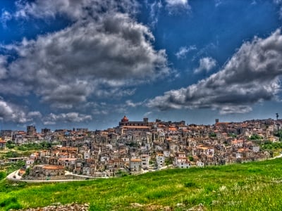 Vue panoramique de Vico del Gargano, un pittoresque village médiéval surplombé par des nuages dramatiques.