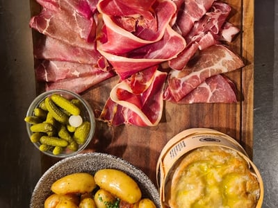 Charcuterie board with potatoes, pickles, and a creamy dish, served at Boundary Shoreditch.