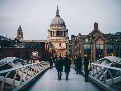 View of St. Paul's Cathedral illuminated at dusk, with passersby on the Millennium Bridge in the City of London.