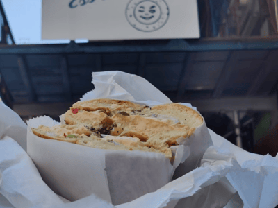 Loaded bagel at Ess-a-Bagel, featuring a flavorful mix of ingredients, with the iconic storefront in the background.