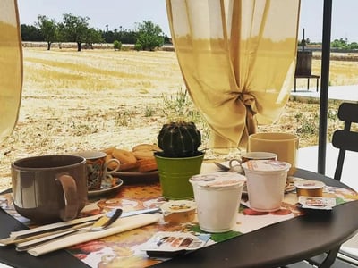 Petit déjeuner sur une table à Casina Pompiliano, avec vue sur les champs dorés et un éclairage doux à travers les rideaux.