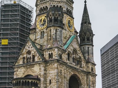 Vue du Kaiser-Wilhelm-Gedächtniskirche, symbole de Berlin, entourée de bâtiments modernes en rénovation.