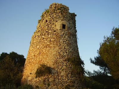 Historic stone tower of Torre Santa Cesarea, surrounded by greenery at sunset, reflecting the local heritage.