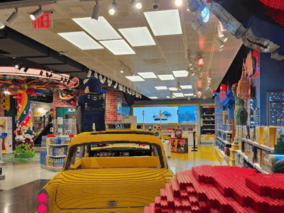 Colorful interior of the LEGO® Store Fifth Avenue, featuring a LEGO brick taxi and iconic figurines in the background.