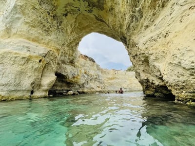 Serene beach of Torre Sant'Andrea, with a beautiful rock arch and swimmers enjoying the crystal-clear waters.