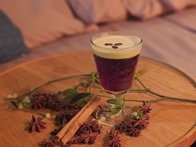 Elegant cocktail on a wooden table, decorated with spices and herbs, at Boundary Shoreditch, evoking a cozy atmosphere.