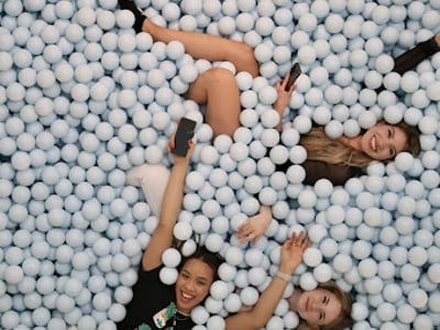 Trois femmes s'amusent dans un océan de balles bleues à Color Factory NYC, créant une atmosphère joyeuse et colorée.