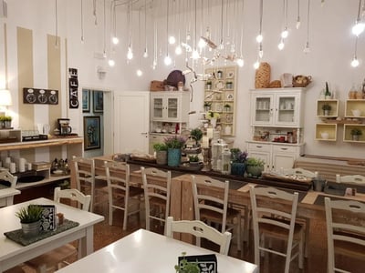 Un café moderne et accueillant au Palazzo Bignami, avec une grande table en bois et des plantes décoratives.