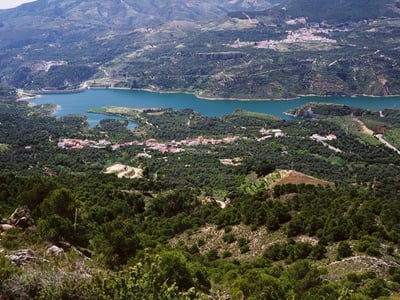 Panoramic view of Béznar, surrounded by lush hills and the emerald lake, showcasing the natural beauty of the region.