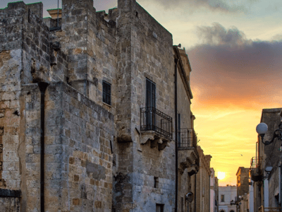 Rue pittoresque de Maruggio au coucher du soleil, mettant en valeur l'architecture en pierre et l'atmosphère méditerranéenne.