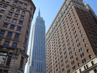 The Empire State Building stands majestically among buildings with varied architectures in Manhattan.