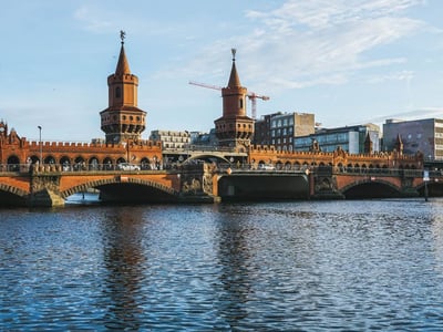 Pont Oberbaumbrücke avec ses tours emblématiques, reflétant dans l'eau, entouré de bâtiments modernes à Berlin.