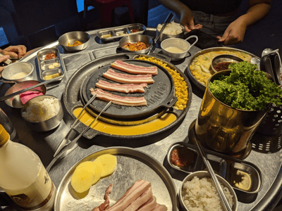 Répartition de plats coréens au Han BBQ, avec du porc grillé, des accompagnements variés et des sauces délicieuses.