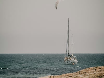 Sailing boat navigating on the Mediterranean Sea near Orihuela, with a bird flying above the waves.
