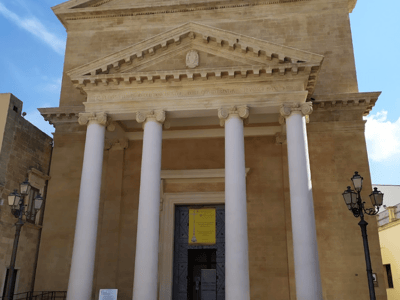 Neoclassical facade of the Saint John the Baptist church in Ugento, characterized by its majestic columns and stone architecture.