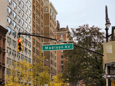 Madison Avenue with autumn-colored trees and iconic New York buildings in the background.