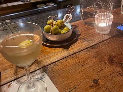 Refined cocktail and olives on a wooden bar, creating a warm atmosphere at the Discount Suit Company.