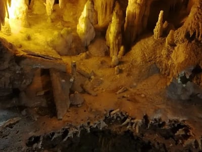 Formation rocheuse spectaculaire illuminée à l'intérieur des grottes de Castellana, révélant des stalactites et stalagmites.