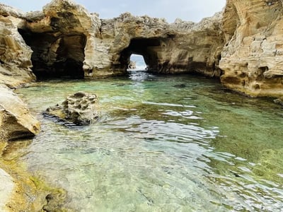 Crystal clear waters and spectacular rock formations at Marina Serra, offering a view of a natural passage.