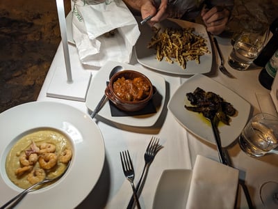 Repas savoureux à Grotta nei Sassi avec des plats variés : pâtes, crevettes et ragoût, créant une expérience culinaire unique.