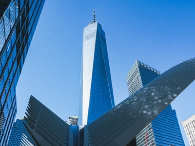 Vue impressionnante de l'Oculus du World Trade Center, avec le One World Trade Center se dressant au fond sous un ciel bleu.