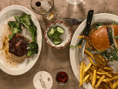 A delicious meal at Ted's Montana Grill, featuring a steak, a burger with fries, and fresh cucumbers.