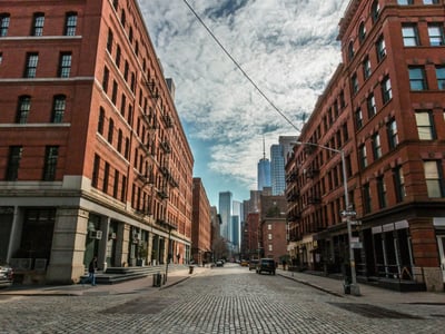 Ruelle pavée de TriBeCa, bordée de bâtiments en briques avec une vue sur les gratte-ciels. Ambiance urbaine dynamique.