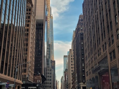 View of Madison Avenue, with modern buildings and the lively atmosphere of the city, under a partly cloudy sky.