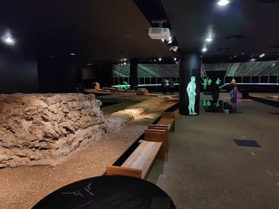 Exposition moderne sur l'histoire au Guildhall, mettant en valeur des ruines anciennes et des silhouettes interactives dans un espace immersif.