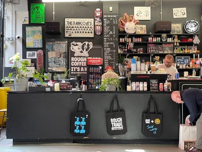 Bar complet à Rough Trade East, avec un employé préparant des boissons au milieu d'une ambiance artistique.