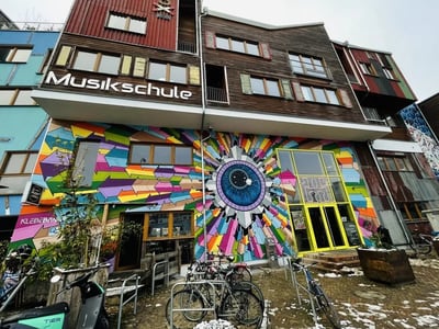 Mural coloré sur le bâtiment de la Musikschule à Holtzmarkt 25, représentant un œil dans un style vibrant et artistique.