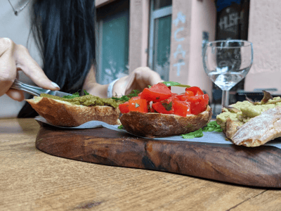 Délicieuses tartines garnies de tomates fraîches et de pesto, servies à Facciola avec un verre de vin en arrière-plan.