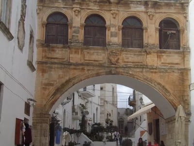 Historical arch in Ostuni, showcasing the picturesque architecture and vibrant social life in a charming café.