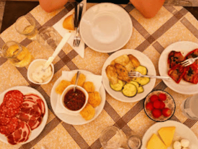 Délicieux repas italien à Osteria Pugliese, avec charcuterie, légumes grillés et fromages artisanaux sur une table en famille.