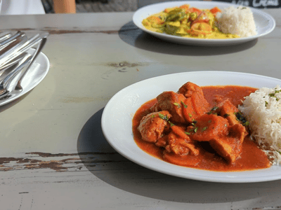Délicieux plat de poulet en sauce servi à Caramel, accompagné de riz et d'un curry vibrant, sur une table en bois.