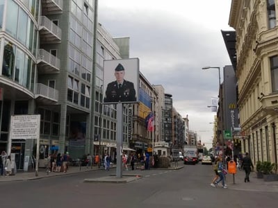 An advertising billboard depicting a soldier, located near Checkpoint Charlie, a symbol of Berlin's history.