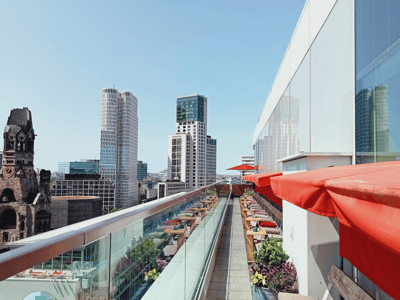 Panoramic view of the Monkey Bar terrace, with red umbrellas and the urban skyline in the background.