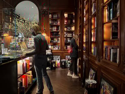 Interior of the Neue Galerie, with visitors exploring books and works of art in a warm and welcoming atmosphere.