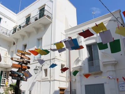 Banderoles colorées flottent au-dessus des rues de Monopoli, ajoutant de la vitalité à l'architecture blanche typique.
