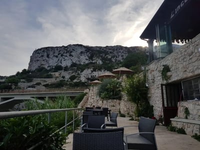 Welcoming terrace at Il Ciolo, with chairs facing the cliffs and a cloudy sky in the background.