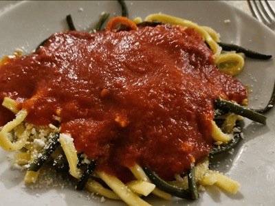 Pâtes aux sauce tomate riche et garnies de fromage, servies dans le cadre chaleureux d'Osteria Pugliese.