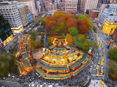 Union Square vibrant in autumn, with colorful trees, lively food trucks, and yellow taxis, reflecting the energy of New York.