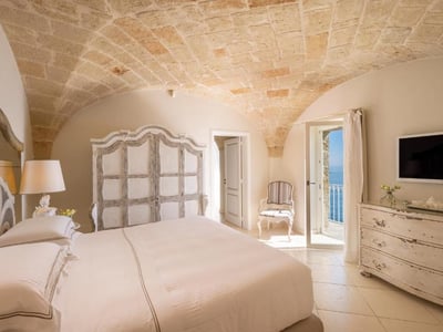 Chambre lumineuse de l'Hôtel Don Ferrante avec vue sur la mer, décorée dans un style élégant et intemporel.