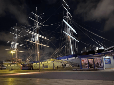 Voiles illuminées des grands voiliers au Pier 16, créant une atmosphère maritime nocturne captivante.