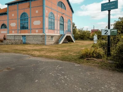 Old station of Sainte-Jamme-sur-Sarthe, colorful building with ornate windows, surrounded by greenery.