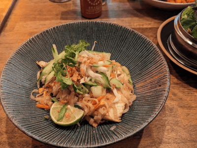 Nouilles sautées servies avec du poulet, des légumes croquants et de la lime, typiques du PHO - Noodlebar.