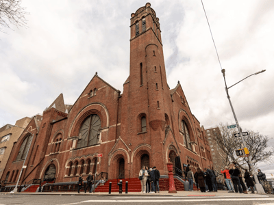Salem United Methodist Church with its red brick facade, welcoming a crowd for a community service in New York.