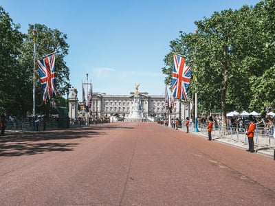 View of Buckingham Palace with the golden statue, British flags, and an empty driveway. Changing of the guard ceremony.