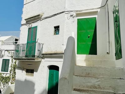 White houses of Ostuni with green doors and a balcony, illustrating the typical architecture of the region.