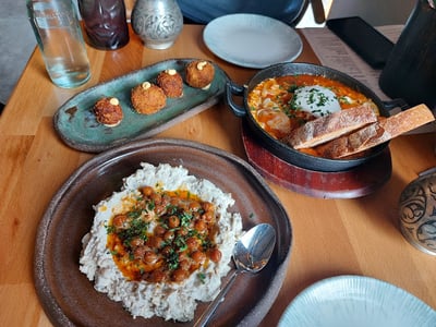 Délicieux plat de houmous garni de pois chiches et d'huile d'olive, accompagné de pain et croquettes au Music & Beans.